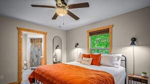 A bedroom with a bed, a ceiling fan, a window, a bedside table, and a bench. - Time Falls Cabin | 2 King BR | 2.5 BA | 2 Porches | Fire Pit | Fast WiFi (Mentone)