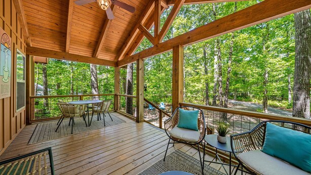 A covered outdoor deck with wooden flooring, a table, chairs, and a sofa. - Time Falls Cabin | 2 King BR | 2.5 BA | 2 Porches | Fire Pit | Fast WiFi (Mentone)