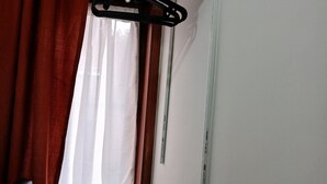 Una habitación con un radiador, una ventana con cortinas y un perchero en la pared.
