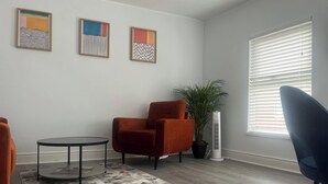 A living room with a round table, two armchairs, a potted plant, and a window with blinds. - 2 Bed Apartment Sleeps 4 - Free Parking (Belfast)