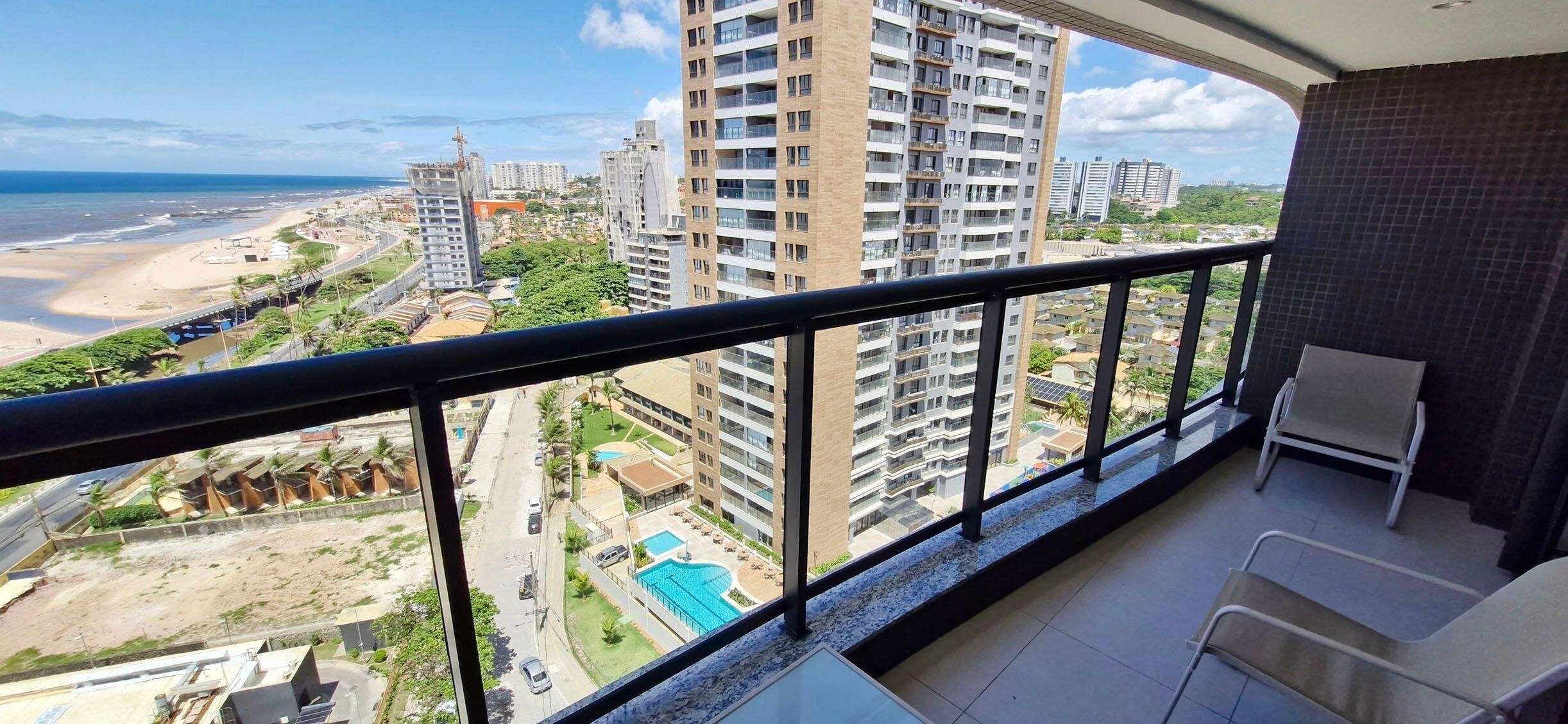 A balcony with a view of a beach, a swimming pool, and high-rise buildings.