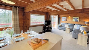 L’intérieur d’un chalet en bois comprend un coin repas, un canapé et un téléviseur.