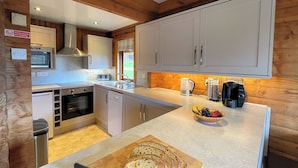 Une cuisine moderne dotée d’un îlot central, d’appareils électroménagers en acier inoxydable et de meubles de rangement en bois.