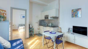 Ett kompakt bostadsutrymme med ett litet kök, en matplats och ett sovrum.