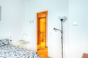 A bedroom with a bed, bedside table, lamp, and a door leading to a bathroom. - The Dome (Firenze)