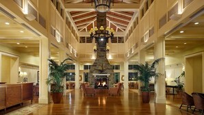 A spacious lobby with a central stone fireplace, high ceilings with wooden beams, and multiple seating areas. - Cozy 2-bedroom condo with AC in charming Bonita Springs (Bonita Springs)