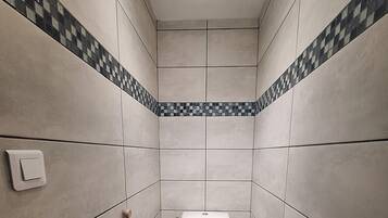 Un baño pequeño y moderno con paredes de azulejos, un inodoro, un bidé y un secamanos.