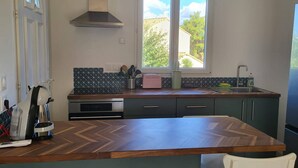 Una cocina con una isla grande, un ventanal con vistas, horno empotrado y extractor de humos.
