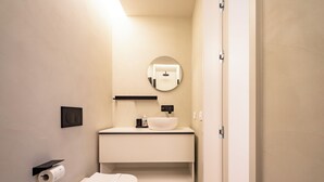 Un baño moderno con inodoro, lavabo y espejo.