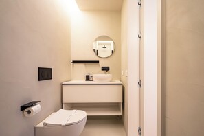 Ein modernes Badezimmer mit Toilette, Waschbecken und Spiegel.