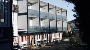 A modern building with multiple balconies, a covered outdoor seating area, and a clear view of the surrounding neighborhood. - Gästehaus Tilly Hotel (Hann. Muenden)