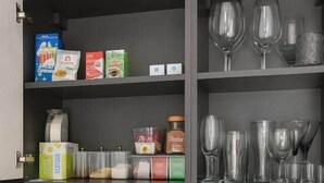 Pieni keittiönurkkaus, jossa on mikroaaltouuni, leivänpaahdin, vedenkeitin ja kahvinkeitin. Siellä on myös hyllyjä, joilla on ruokatarvikkeita ja lasiastioita.