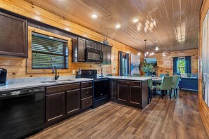 A wooden cabin interior with a kitchen, dining area, and a large window with a mountain view. - Great location, Pigeon Forge: 5 bedroom with theatre, game room, hottub (Pigeon Forge)