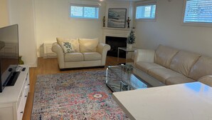 Ein Wohnzimmer mit beiger Couch, Couchtisch, Fernseher und Kamin.