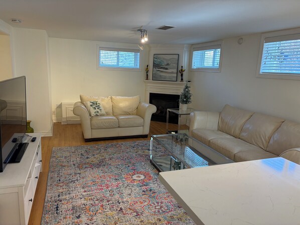 Una sala de estar con un sofá color beige, una mesa de centro, un televisor y una chimenea.