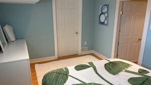 Ein Schlafzimmer mit Bett, Kommode und Tür.