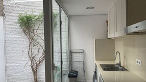 A modern kitchen with a built-in washing machine, a sink, and a drying rack. - Cozy house in the heart of Mataró (Mataró)