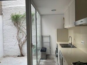 A modern kitchen with a built-in washing machine, a sink, and a drying rack. - Cozy house in the heart of Mataró (Mataró)