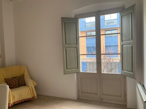 A room with a large window, a chair with a blanket, and a radiator. - Cozy house in the heart of Mataró (Mataró)