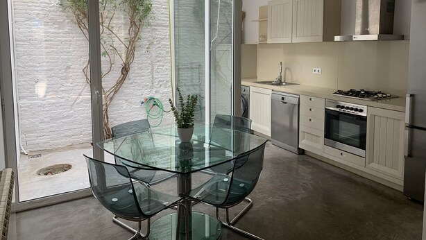 A modern kitchen with a glass dining table, stainless steel appliances, and a view of the outdoors. - Cozy house in the heart of Mataró (Mataró)