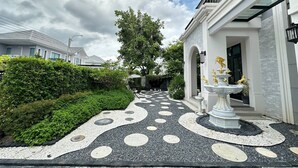 A pathway leading to a building with a fountain and a statue. - House Near Suvarnabhumi Airport (Bangkok)