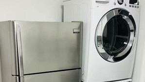 In cucina, un frigorifero in acciaio inossidabile e una lavatrice e asciugatrice affiancate.