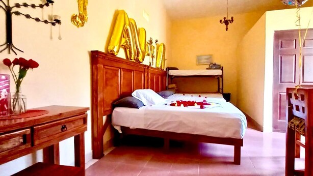 Een slaapkamer met een houten bed, nachtkastje, dressoir en een wandplank met decoratieve spullen.