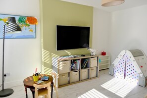 A room with a TV, a desk with a chair, a bookshelf, and a play tent. - Spacious 4BR Home near Derry & Foyle Golf Club (Londonderry)