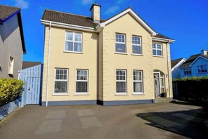 A two-story residential building with a flat roof, multiple windows, and a visible front door. - Spacious 4BR Home near Derry & Foyle Golf Club (Londonderry)