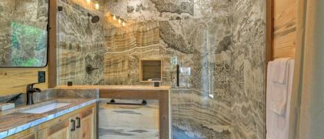 A bathroom with a stone wall, wooden cabinets, and a large mirror.