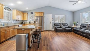Una cocina amplia con armarios de madera, un refrigerador de acero inoxidable y una zona de bar con taburetes.