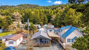 Una zona residencial con casas, un estacionamiento y un cerro cubierto de bosque al fondo.