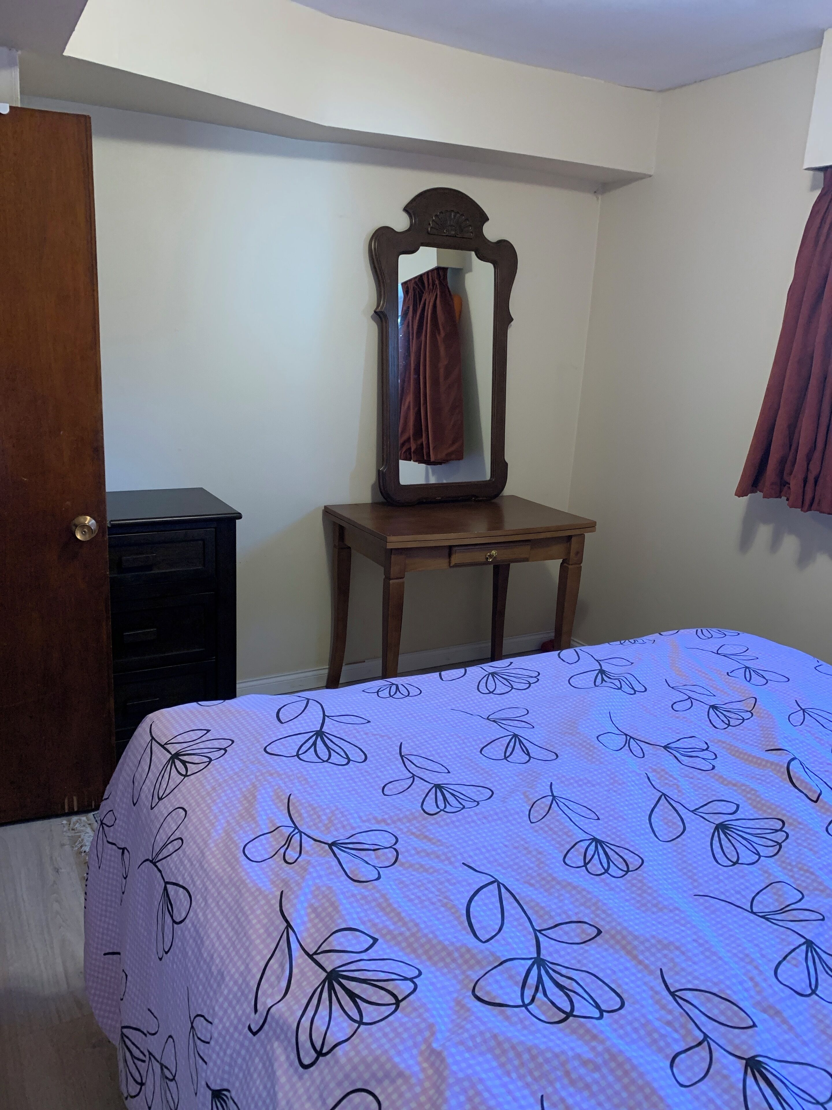 Ein Schlafzimmer mit Bett, Schminktisch, Spiegel und Tür.