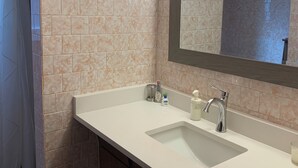 Un baño con dos lavamanos, un espejo y zona de ducha.