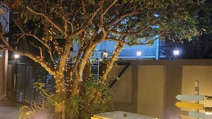 Un espace extérieur aménagé avec une table et des chaises, entouré de gazon synthétique et éclairé par des luminaires encastrés dans le sol.