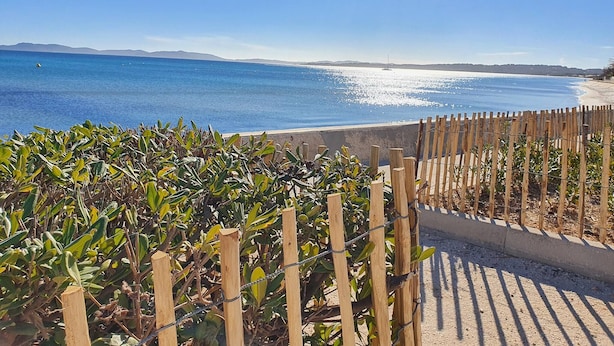 A coastal view with a wooden fence, a clear blue sky, and a distant shoreline. - Les Photinias Giens Peninsula Beach King-Size Bed (Hyères)
