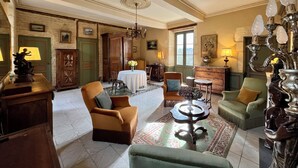 A spacious living room with a high ceiling, a chandelier, and a large window. - La chartreuse de Caville, swimming pool & nature (Eyraud-Crempse-Maurens)