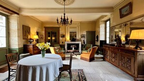 A formal dining room with a round table, chairs, a chandelier, and a fireplace. - La chartreuse de Caville, swimming pool & nature (Eyraud-Crempse-Maurens)