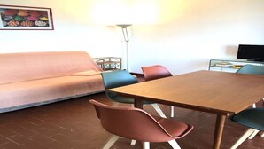 Un comedor con una mesa y sillas de madera, un sofá y una televisión.