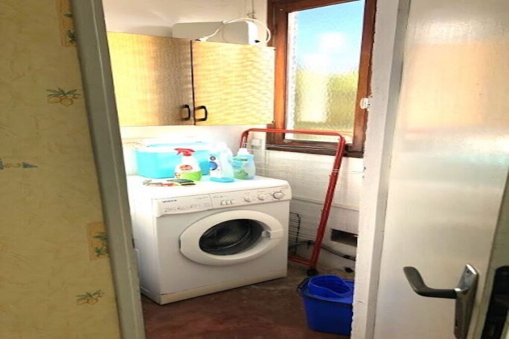 Une petite buanderie équipée d’un lave-linge, d’un étendoir et d’une fenêtre donnant sur un paysage agréable.
