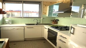Eine kompakte Küche mit Geschirrspüler, Backofen, Herd und Kühlschrank.