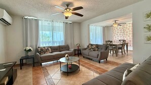 A living room with two sofas, a coffee table, and a dining area with a table and chairs. - Golden Dream Villa 2nd floor A (Isabela)