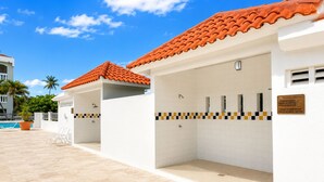 Een zwembadgedeelte met een betegelde vloer, een dak van rode tegels en een wit gebouw met een betegelde muur.