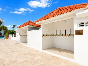 A poolside area with a tiled floor, a red-tiled roof, and a white building with a tiled wall. - Golden Dream Villa 2nd floor A (Isabela)