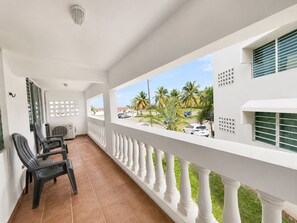 A balcony with white balustrades, a view of palm trees, and a street with parked cars. - Golden Dream Villa 2nd floor A (Isabela)