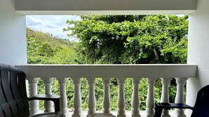 A balcony with white balustrades, two black chairs, and a small table. - Golden Dream Villa 2nd floor A (Isabela)