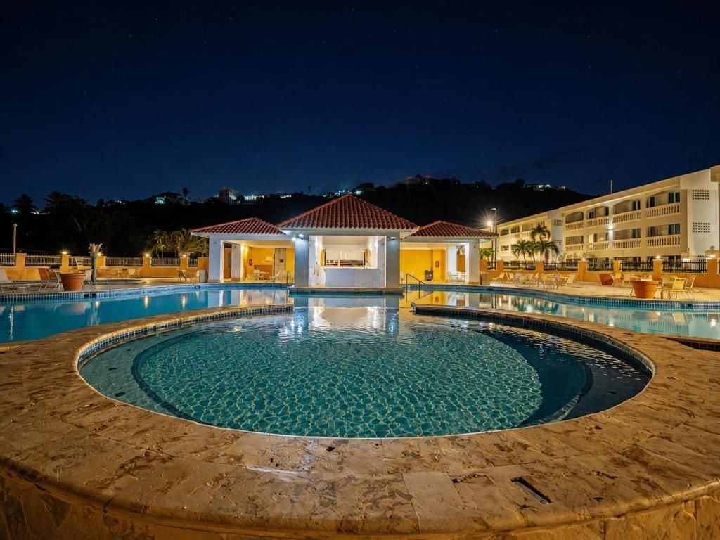 En pool med cirkelformad design, ett avskärmat sittområde och en byggnad i bakgrunden.