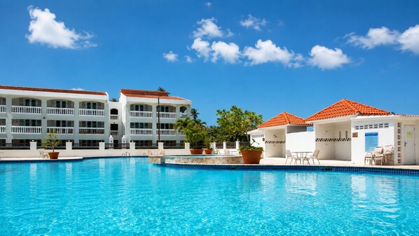 A swimming pool with a clear blue sky, a white building with balconies, and potted plants. - Golden Dream Villa 2nd floor A (Isabela)