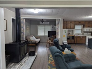 A living room with a fireplace, sofa, television, and kitchen area.
