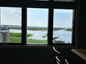 A room with a large window overlooking a calm lake with boats and a dock.